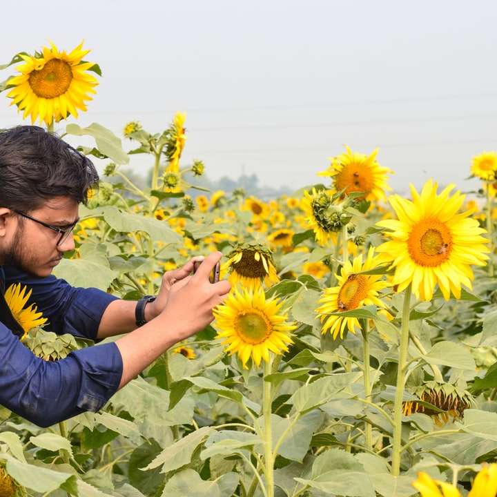 Man in Blauwe Hoodie Holding Sunflower overdag online puzzel