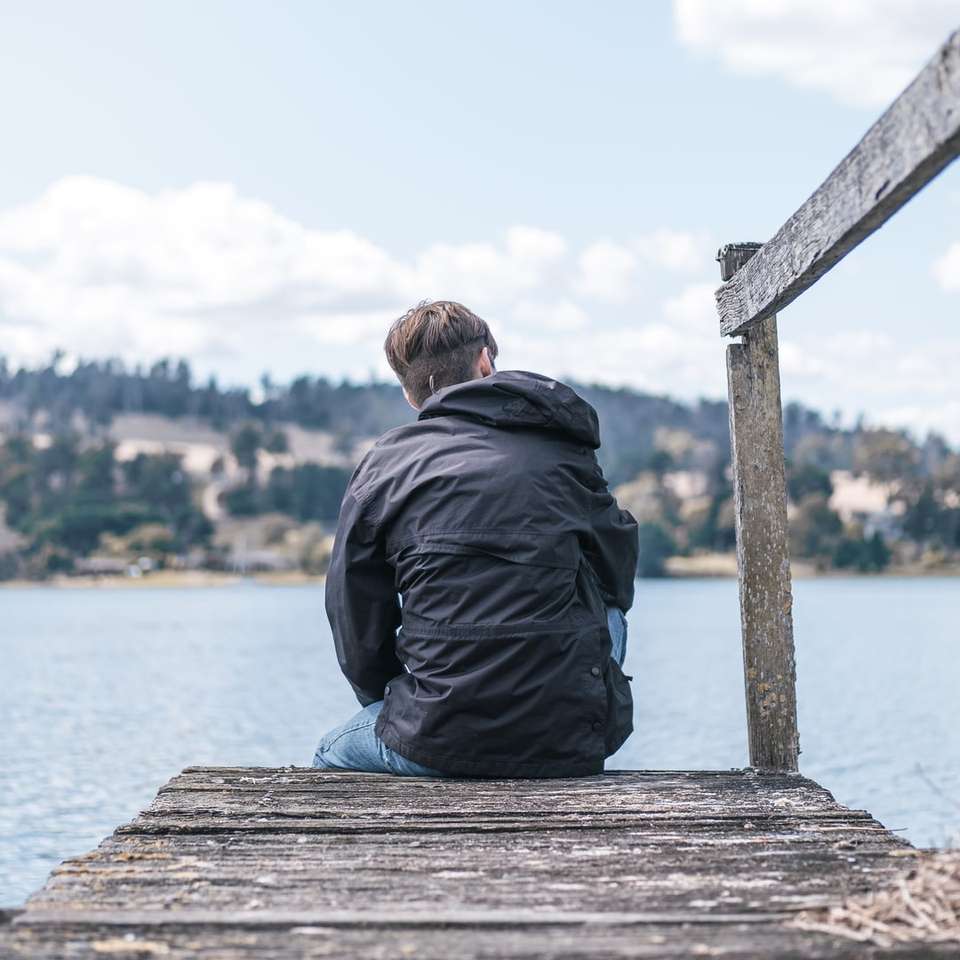 férfi fekete kabát ül a fából készült dokkban nappali nappal online puzzle