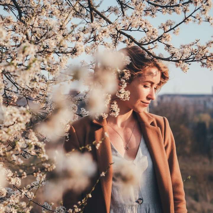 Femme en manteau brun debout sous l'arbre blanc puzzle en ligne