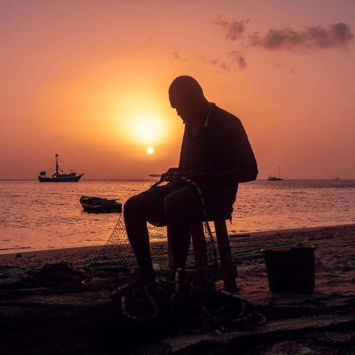silhouette of man sitting on chair near body of water online puzzle