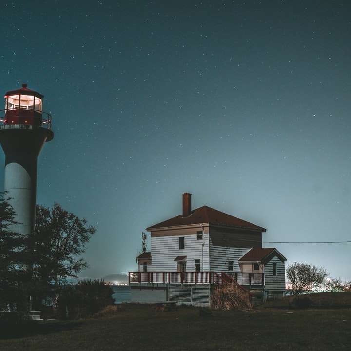 Biała i czerwona latarnia morska pod błękitnym niebem w nocy puzzle online