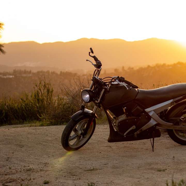 Motocicleta negra en arena marrón durante la puesta del sol puzzle deslizante online