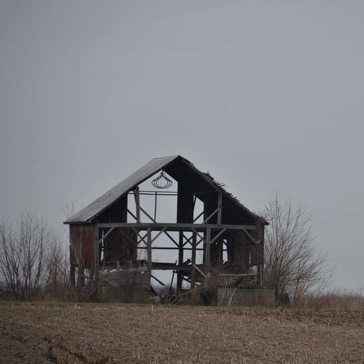 Casa de madeira marrom no campo de grama marrom sob o céu branco puzzle deslizante online