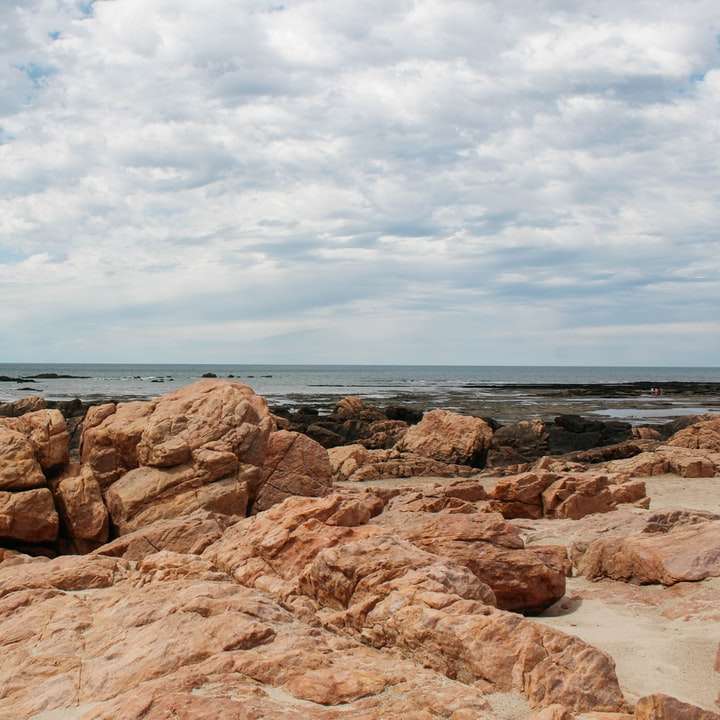 Formazione rocciosa marrone vicino al corpo dell'acqua durante il giorno puzzle online