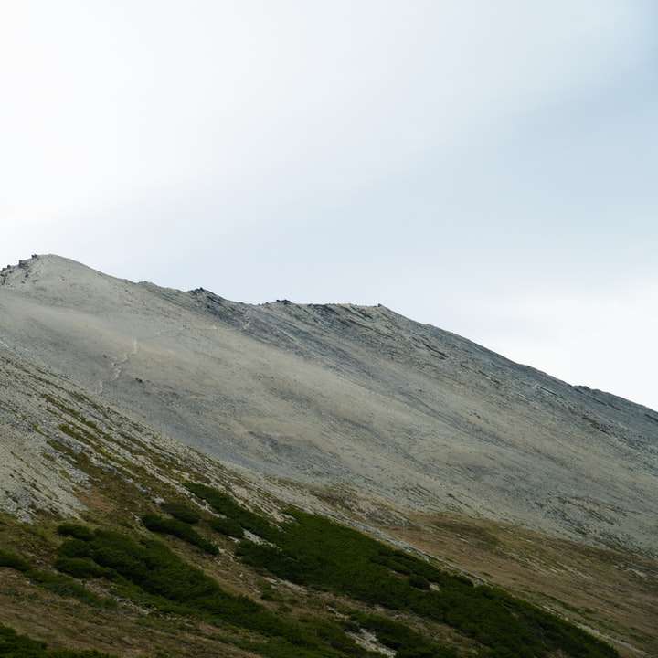 Montagna verde e grigia sotto il cielo bianco durante il giorno puzzle scorrevole online