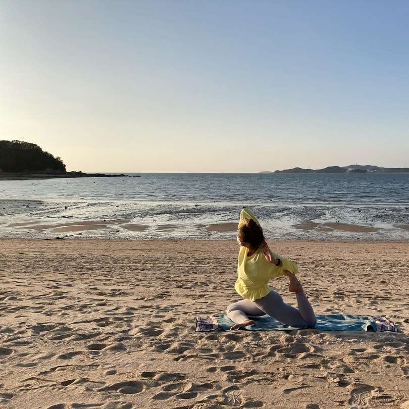 Жена в жълта рокля седи на плажния бряг през деня онлайн пъзел