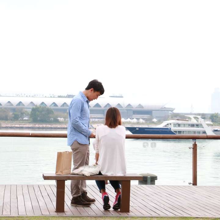 Muž a žena sedí na hnědé dřevěné lavičce u těla posuvné puzzle online