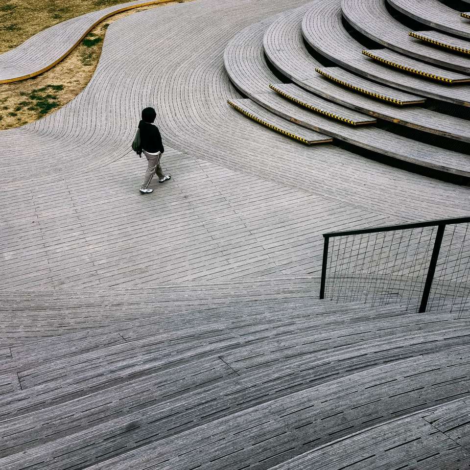 man in black jacket walking on gray concrete pathway sliding puzzle online