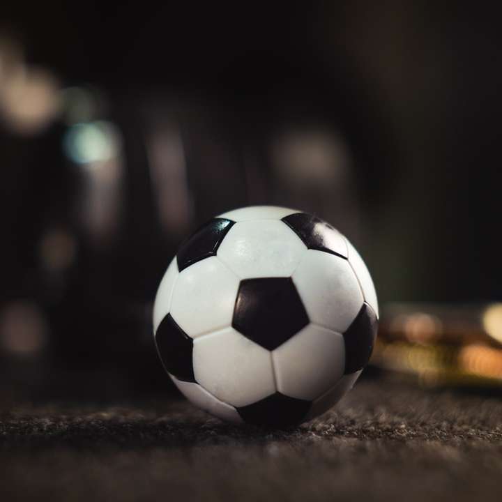 Λευκή και μαύρη μπάλα ποδοσφαίρου σε μαύρη άμμο συρόμενο παζλ online