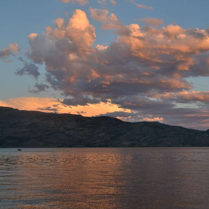 Σώμα νερού κοντά στο βουνό κάτω από συννεφιασμένο ουρανό κατά τη διάρκεια της ημέρας συρόμενο παζλ online