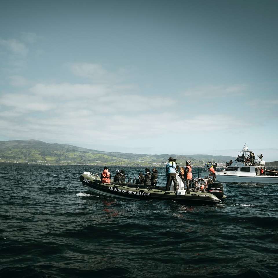 люди катаються на чорно-червоному човні на морі в денний час онлайн пазл