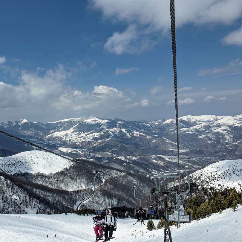 Oamenii de echitatie de schi pe muntele acoperite de zăpadă puzzle online