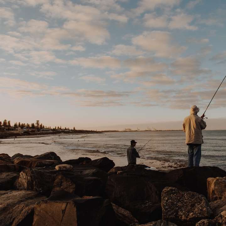 Man i vit skjorta och svarta byxor som håller fiskestången Pussel online