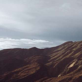 Bruine en grijze bergen onder witte wolken en blauwe hemel online puzzel