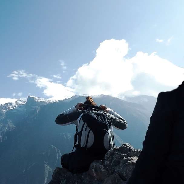 Mann in der schwarzen Jacke, die Foto des schneebedeckten Bergs nimmt Schiebepuzzle online