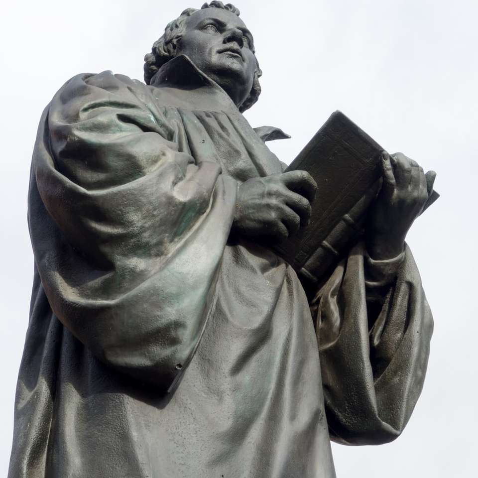 Hombre en abrigo con estatua de libro rompecabezas en línea