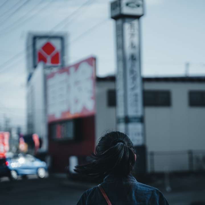 Mujer en la chaqueta de mezclilla azul de pie cerca del edificio blanco rompecabezas en línea