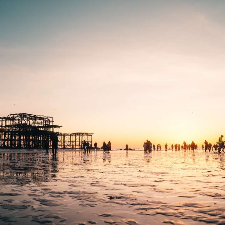 Människor på stranden under solnedgången Pussel online