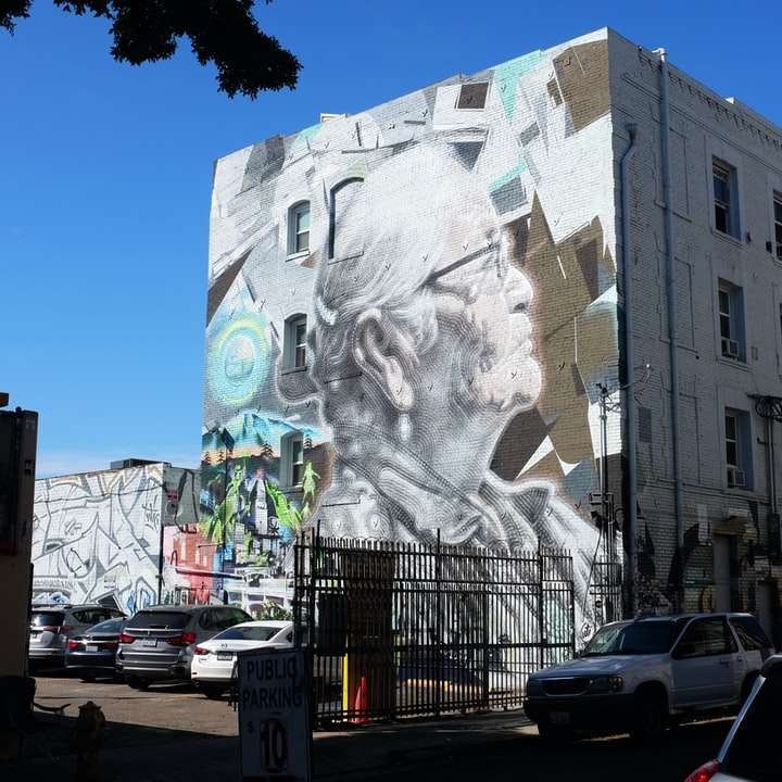 Edificio de concreto blanco con arte de la pared de la cara humana. rompecabezas en línea