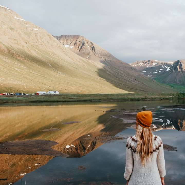 Kobieta w białym swetrze stoi blisko jeziora podczas dnia puzzle przesuwne online