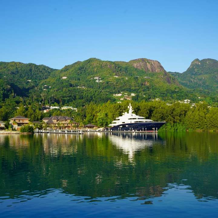 Barca bianca sull'acqua vicino al montagna verde durante il giorno puzzle scorrevole online