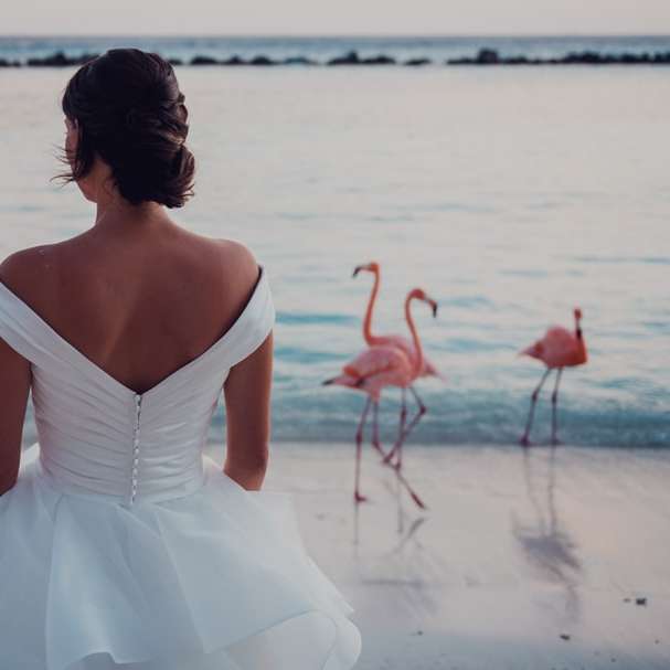 Жена в бяла рокля стоя на плажа през деня плъзгащ се пъзел онлайн