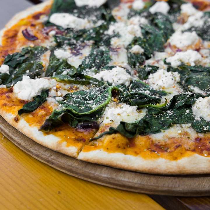 Pizza med gröna blad på brunt träbord glidande pussel online