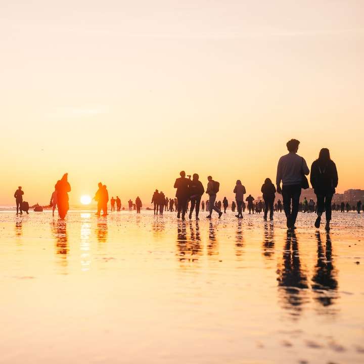Ludzie na plaży podczas zachodu słońca puzzle przesuwne online