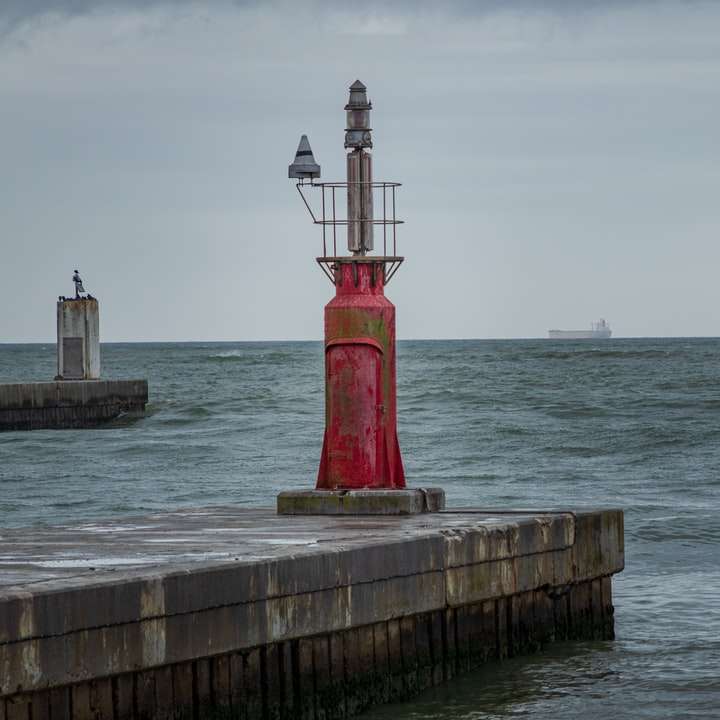 rot und weißer Leuchtturm in der Nähe von Wasser des Wassers tagsüber Online-Puzzle