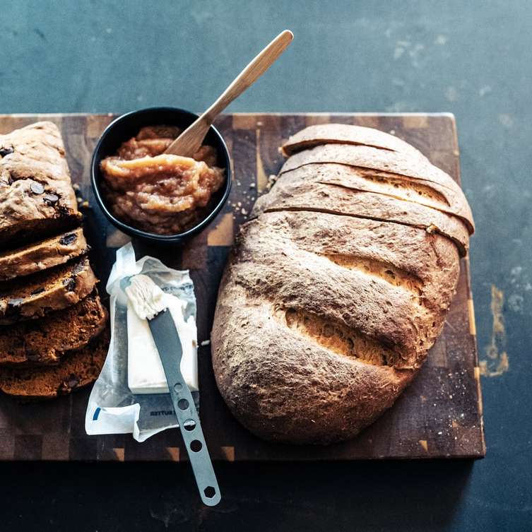 Ψωμί σε μαύρο κεραμικό πιάτο δίπλα στο μαχαίρι από ανοξείδωτο χάλυβα online παζλ