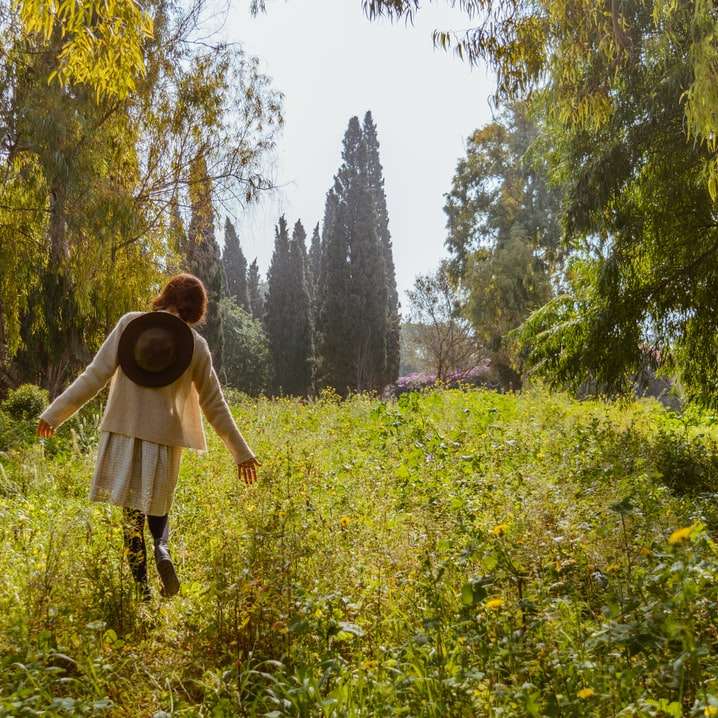 Kobieta w brown kurtki pozyci na zielonej trawy polu puzzle online