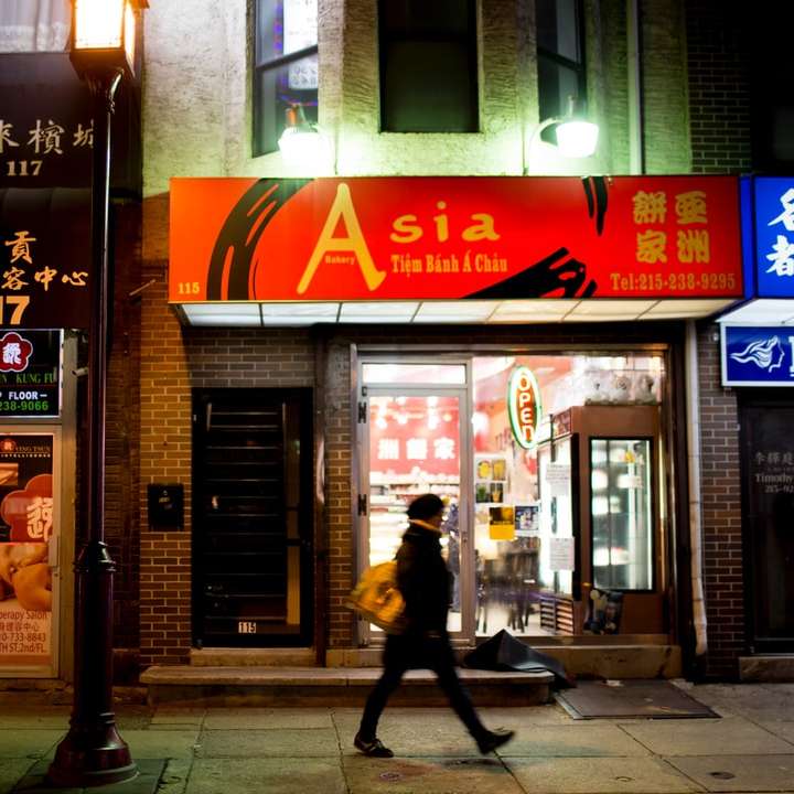 Mężczyzna w czarnej kurtce spaceru na chodniku w pobliżu sklepu puzzle przesuwne online