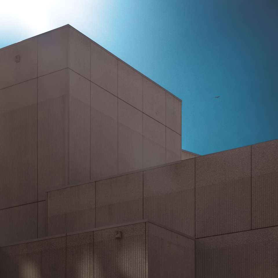 Сива бетонна сграда под синьо небе през деня онлайн пъзел