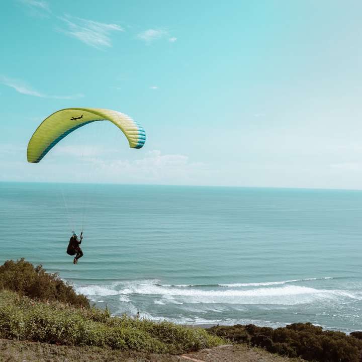person in black shirt on yellow parachute over blue sea online puzzle