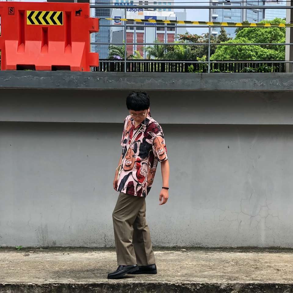 Omul în pantaloni maro în apropierea clădirii roșii și albe puzzle online