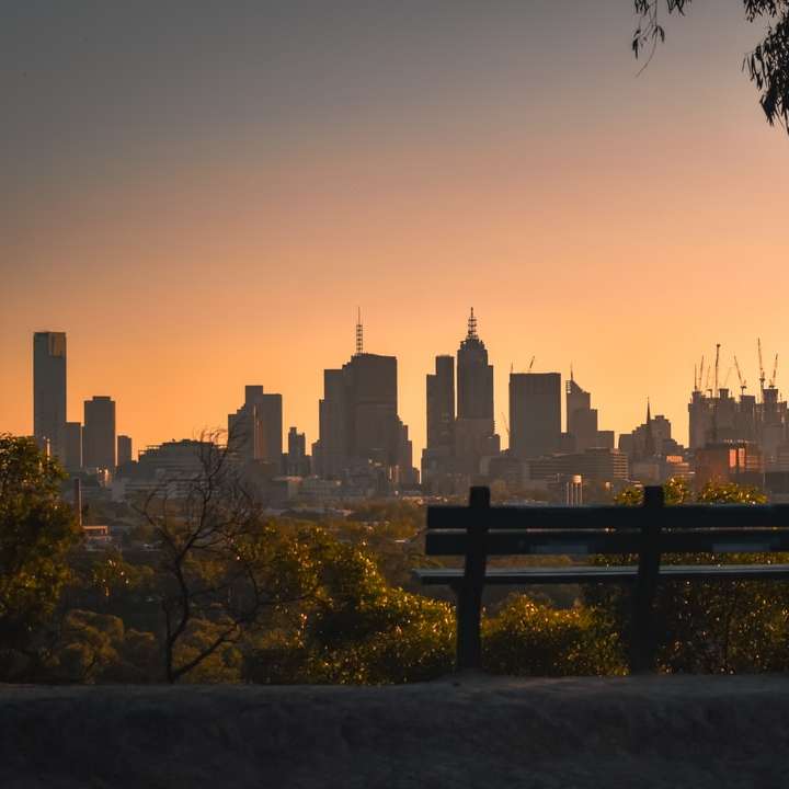 Siluetta della panchina vicino agli edifici della città durante il tramonto puzzle scorrevole online