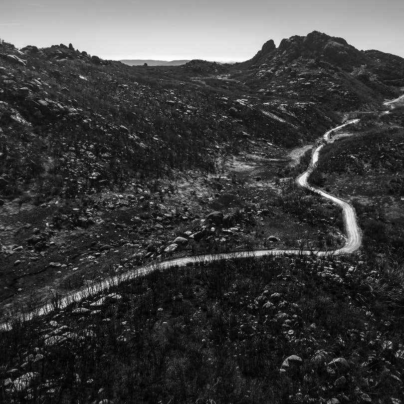 Grayscale fotografie de drum între munți puzzle online