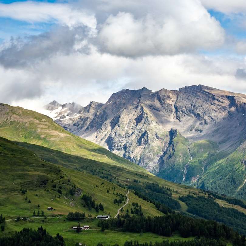 Montanhas verdes e brancas sob nuvens brancas durante o dia puzzle deslizante online