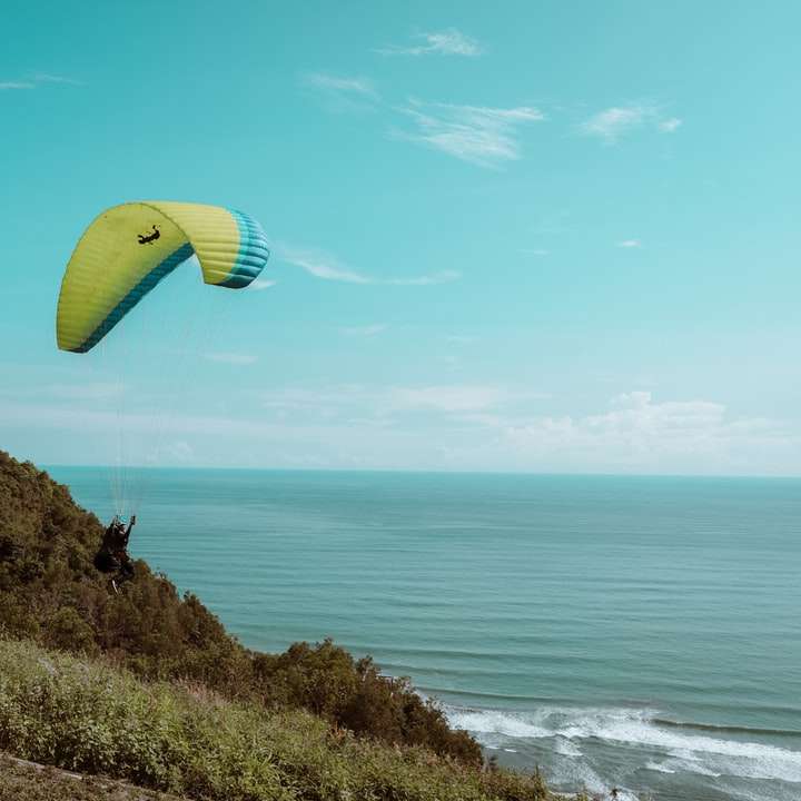 Parachute amarelo e verde sobre o mar durante o dia puzzle online