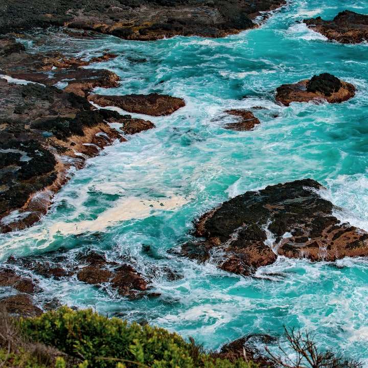 Πράσινο γρασίδι σε καφέ σχηματισμό βράχου δίπλα στη γαλάζια θάλασσα online παζλ