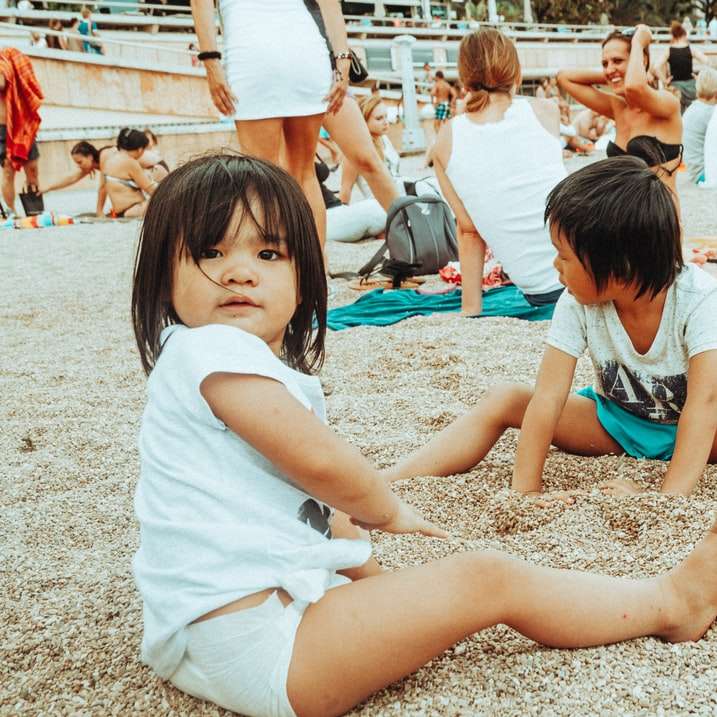 Chica en camiseta blanca sentado en la arena durante el día puzzle deslizante online