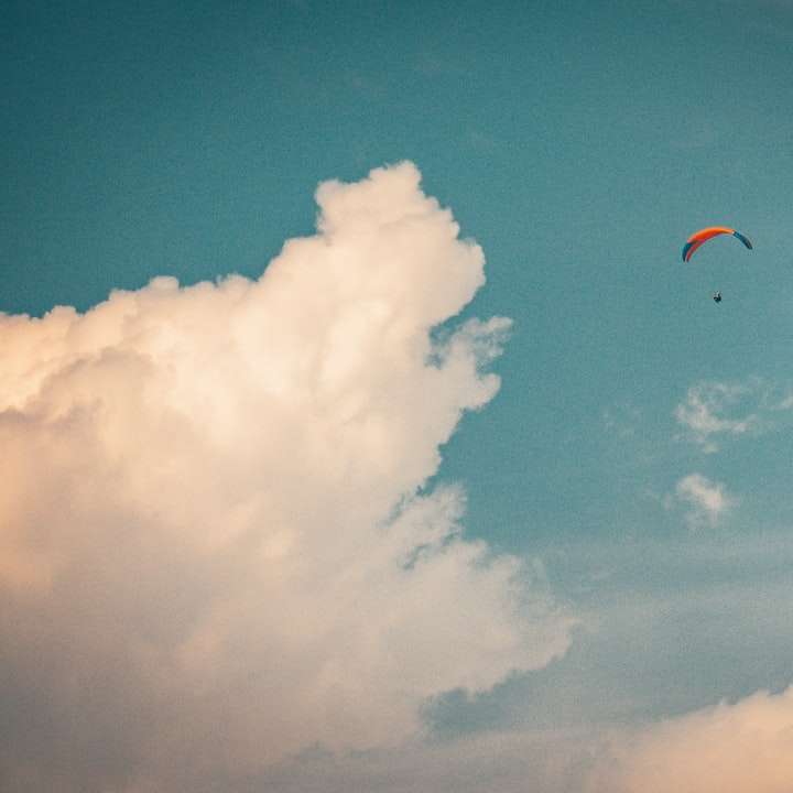 Persona en paracaídas bajo el cielo azul durante el día. rompecabezas en línea