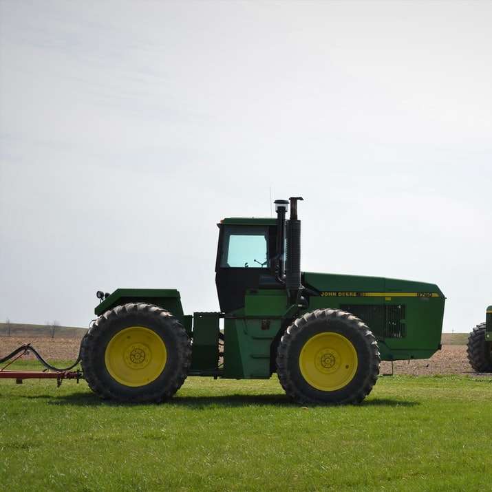 Tracteur vert sur le champ d'herbe verte sous un ciel blanc puzzle en ligne