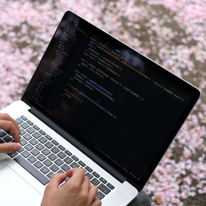 Person som använder MacBook Pro på rosa och vit blommig textil glidande pussel online