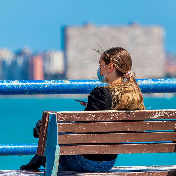 Donna in giacca nera che si siede sulla panca di legno marrone puzzle online