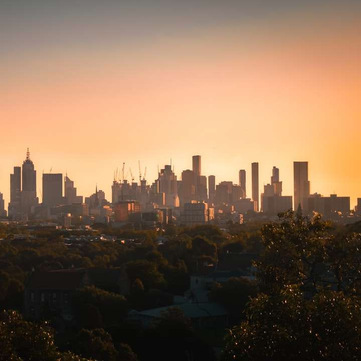 Skyline oraș în timpul apusului cu cerul portocaliu alunecare puzzle online