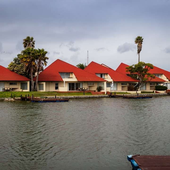 Rött och vitt hus bredvid kroppen av vatten under dagtid glidande pussel online