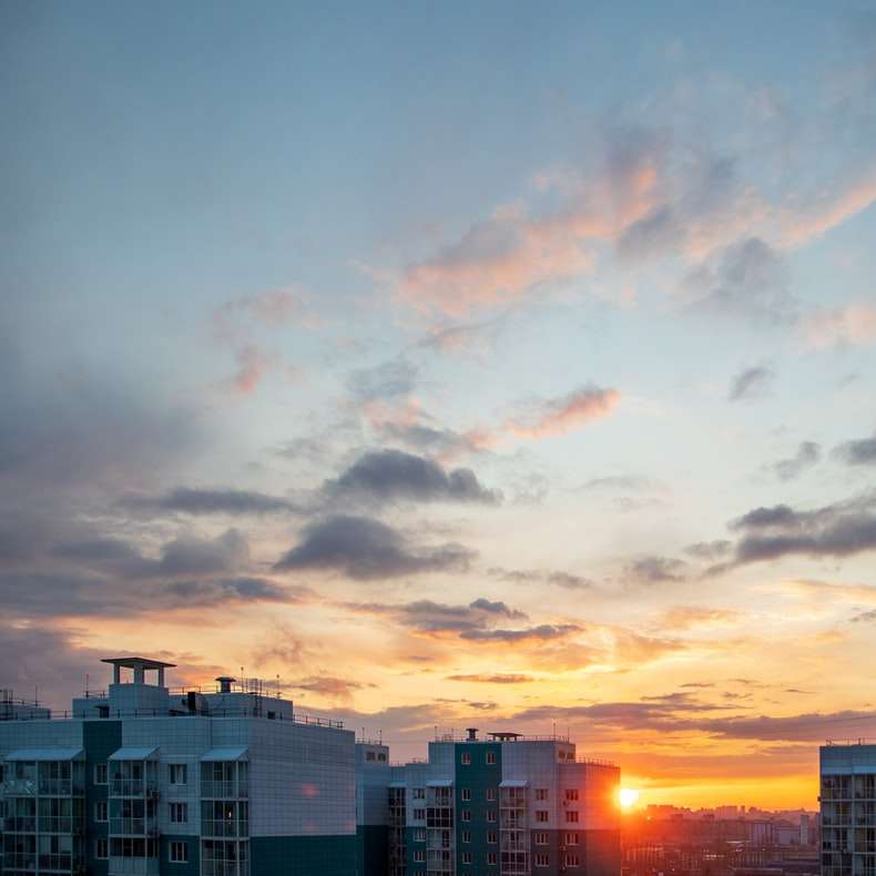 Κτίρια της πόλης κάτω από συννεφιασμένο ουρανό κατά τη διάρκεια του ηλιοβασιλέματος συρόμενο παζλ online