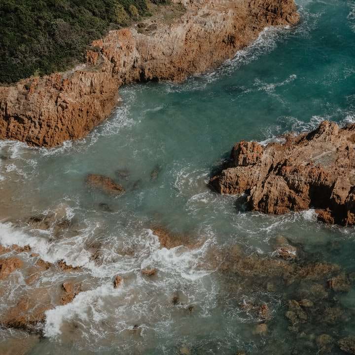 Bruine en groene rotsachtige berg naast lichaam van water schuifpuzzel online