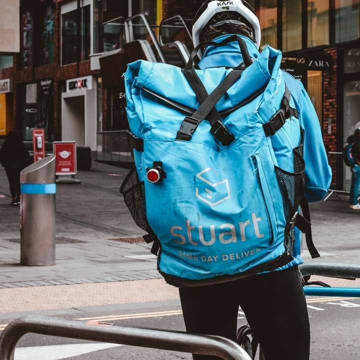 Person im blauen und orange Rucksack, der auf Bürgersteig geht Online-Puzzle